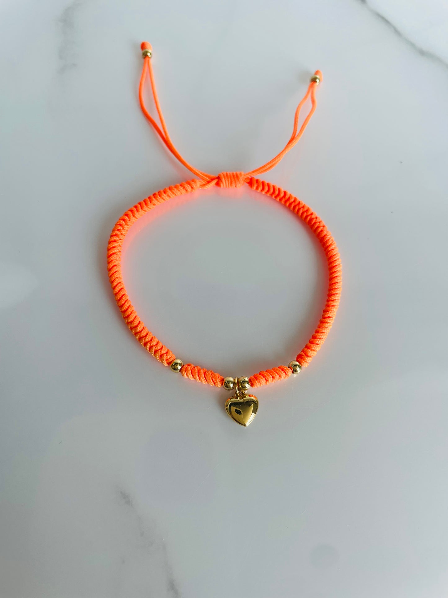 Pulsera tejida naranja, corazón